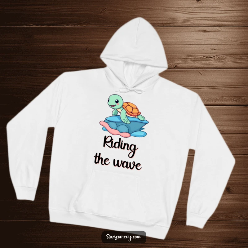 Funny hoodie featuring a cheerful sea turtle riding a large, colorful shell like a surfboard, bringing beachy humor and warmth.